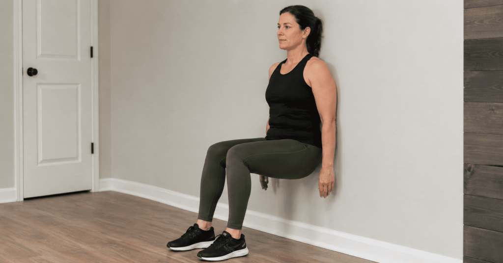Person doing a wall sit with correct form against a wall
