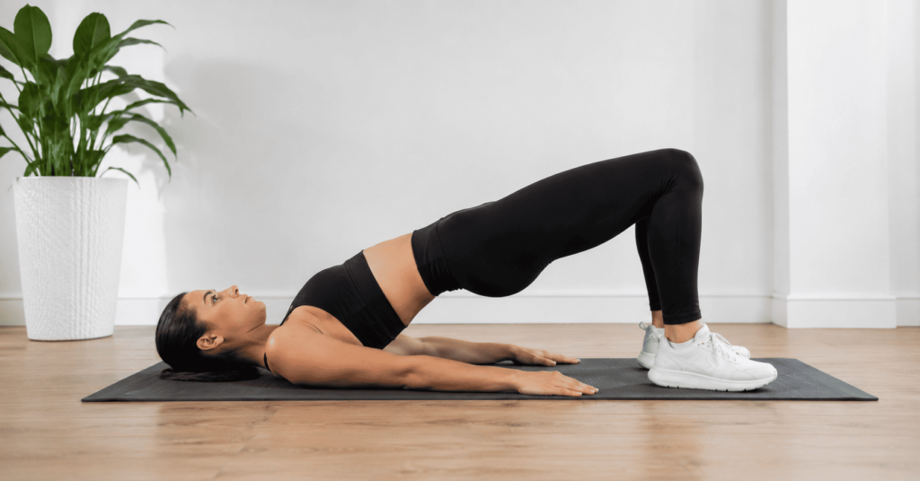 woman performing glute bridge exercise on yoga mat